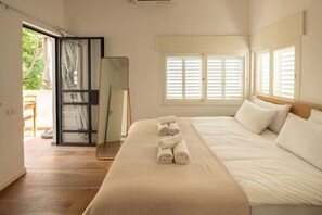 A bedroom with a bed, a window with shutters, a door leading to an outdoor area, and a mirror.