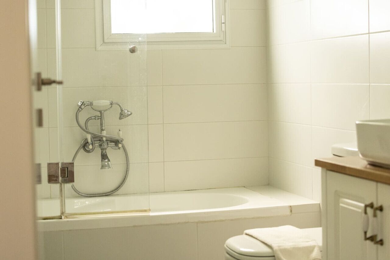 A bathroom with a bathtub, a toilet, and a window above the tub.