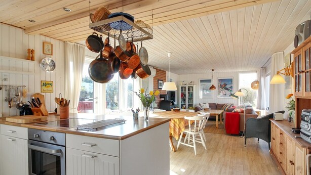 Une cuisine moderne dotée d’un îlot central, de meubles en bois et d’un porte-ustensiles suspendu.