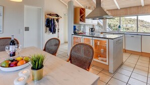 Cozinha moderna com ilha central, vigas de madeira no teto e vista para o exterior.