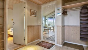 Un pasillo con paneles de madera, una cama en la habitación contigua, una zona de comedor con sillas y vistas a través de un ventanal.