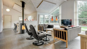 A modern living room with a fireplace, leather chairs, a sofa, and a TV.