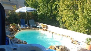 A hot tub with a pool in the background, surrounded by lounge chairs and potted plants. - Suite Noelie, son Ecran de Cinema et sa Baignoire d Époque (Brassac)