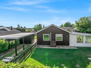 Une maison moderne dotée d’un patio couvert, d’une cour clôturée et d’une pelouse bien entretenue.