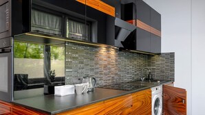 Une cuisine moderne dotée d’un plan de travail en bois, d’un lave-linge encastré et d’un crédence carrelée.
