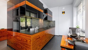 Une cuisine moderne dotée d’un îlot central, d’appareils électroménagers intégrés et d’un coin repas avec une table dressée pour deux personnes.