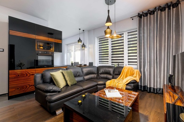 The modern interior of the stylish living room with a black leather sofa behind which is the kitchenette.
