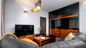 Un salon moderne avec un téléviseur à écran plat, un canapé en cuir, une table basse en bois et un grand miroir.