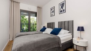 Un dormitorio moderno con dos camas, una ventana con cortinas y una mesita de noche con una lámpara.