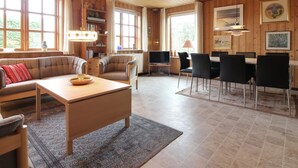 A cozy living room with a sofa, coffee table, and a dining area with chairs and a table. There are bookshelves and a TV in the room. - "Ehmi" - 500m from the sea by Interhome (Løkken)