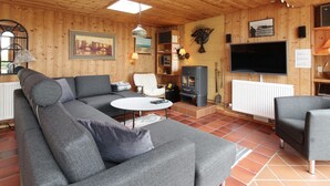 A cozy wooden cabin interior with a sectional sofa, a white coffee table, a fireplace, and a television. - "Ehmi" - 500m from the sea by Interhome (Løkken)