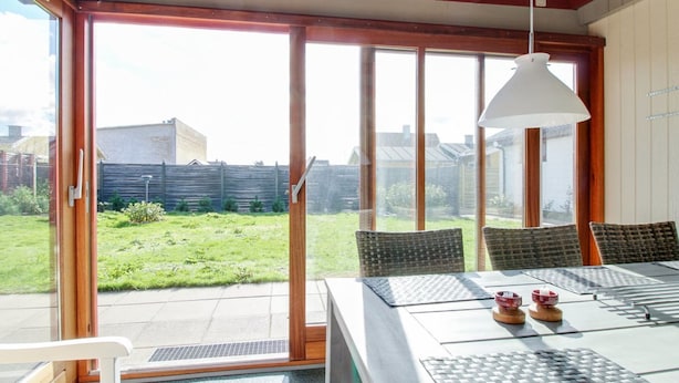 A dining area with a table, chairs, and a view of a garden through large sliding glass doors. - "Ehmi" - 500m from the sea by Interhome (Løkken)