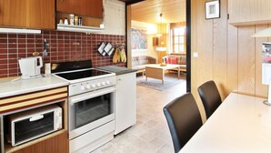 A compact kitchen with a stove, oven, and microwave. There is a dining area with a table and chairs. - "Ehmi" - 500m from the sea by Interhome (Løkken)