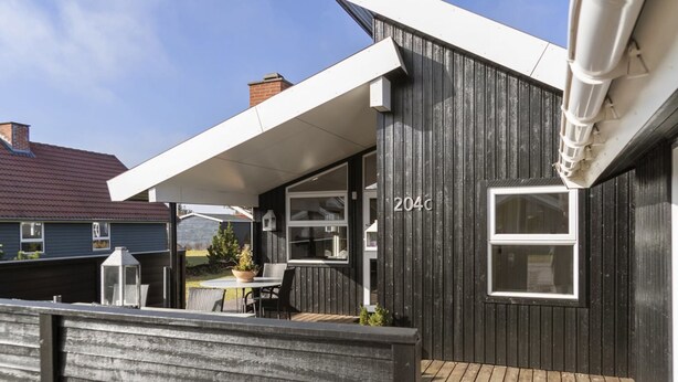 Uma casa moderna com varanda, alpendre coberto e o número '204c' visível.