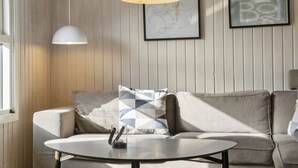 Uma sala de estar moderna com um sofá, uma mesa de centro redonda e iluminação pendente.