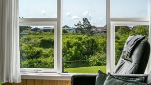 Une pièce dotée d’une grande fenêtre donnant sur un jardin verdoyant et des maisons.