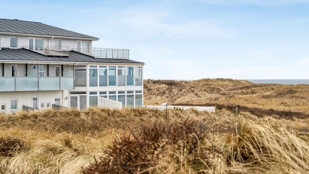 Un bâtiment moderne situé sur la côte, doté de plusieurs étages, de grandes fenêtres et d’un toit plat.