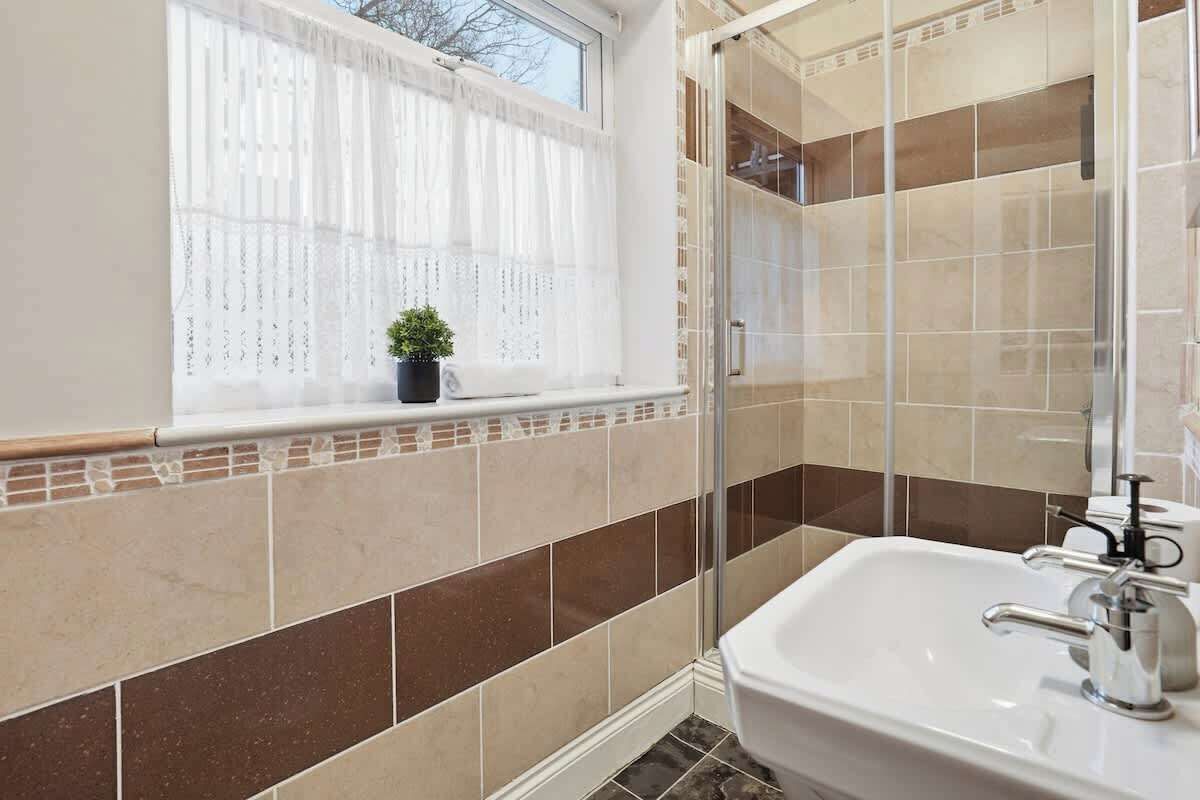 Un baño con ventana, lavabo y zona de ducha.