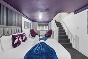 Ein Hotelzimmer mit einem Bett, zwei Stühlen, einer Treppe und einem Fenster.