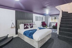 Une chambre à coucher avec un lit, une chaise, un bureau et un escalier.