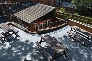 Eine Dachterrasse mit Holzbänken und einem kleinen Gebäude mit Satteldach.