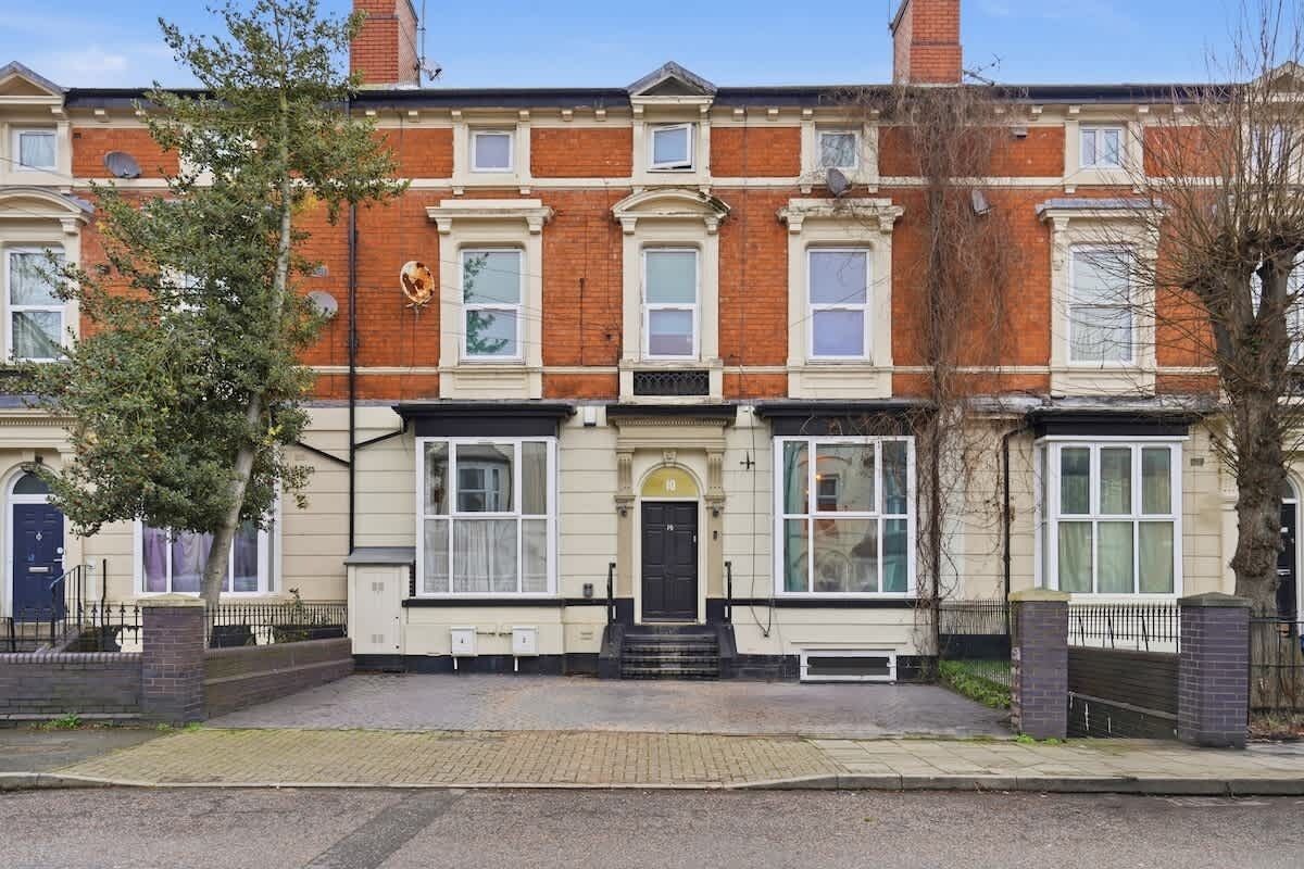 A row of terraced houses with a central entrance, brick facade, and white-framed windows.