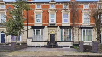 A row of terraced houses with a central entrance, brick facade, and white-framed windows.