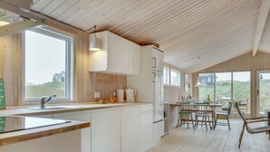 A modern kitchen with white cabinets, a large window, and a dining area with chairs and a table.