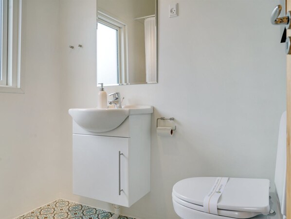 A bathroom with a white sink, mirror, and toilet.