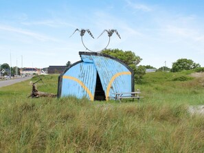 A rustic, weathered blue structure with a curved entrance and two metal sculptures resembling insects on top. - "Helja" - 125m from the sea by Interhome (Hals)