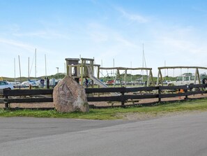 A playground with a slide and climbing structures, a large rock with carvings, and a parking area with boats and vehicles. - "Helja" - 125m from the sea by Interhome (Hals)