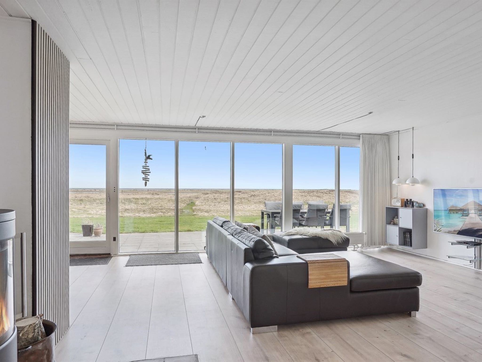 A modern living room with a large sofa, a fireplace, and a view of the outdoors.