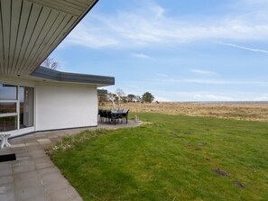 Une maison moderne dotée d’un patio couvert et d’une pelouse.