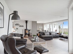 Un salon moderne avec des canapés en cuir, une cheminée et de grandes fenêtres.
