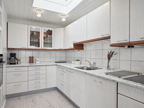 A modern kitchen with white cabinetry, a built-in oven, and a skylight above the countertop. - "Helja" - 125m from the sea by Interhome (Hals)