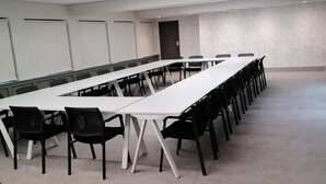 A conference room with a long table and chairs, white walls, and a carpeted floor. - All Africa House (Cape Town)