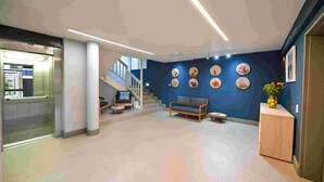 A spacious lobby with a staircase, a sofa, a coffee table, and a cabinet. - All Africa House (Cape Town)