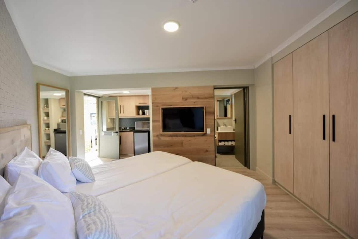A bedroom with a large bed, a TV mounted on the wall, and a wardrobe.