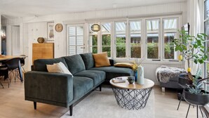 Un salon moderne avec un canapé d’angle, une table basse ronde et un coin repas comprenant des chaises et une table.