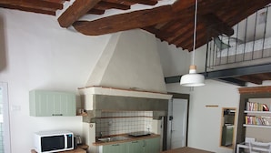 A kitchen with a microwave, sink, and green cabinets. There is a wooden dining table with chairs and a hanging light fixture. - Loft - Le Maioliche (Montelupo Fiorentino)