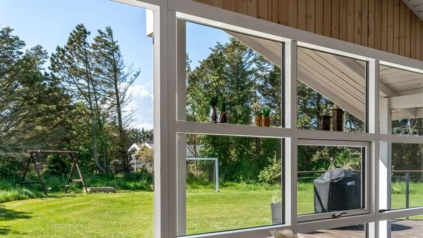 Ein modernes Haus mit großen Fenstern mit Blick auf einen gepflegten Rasen und Garten.