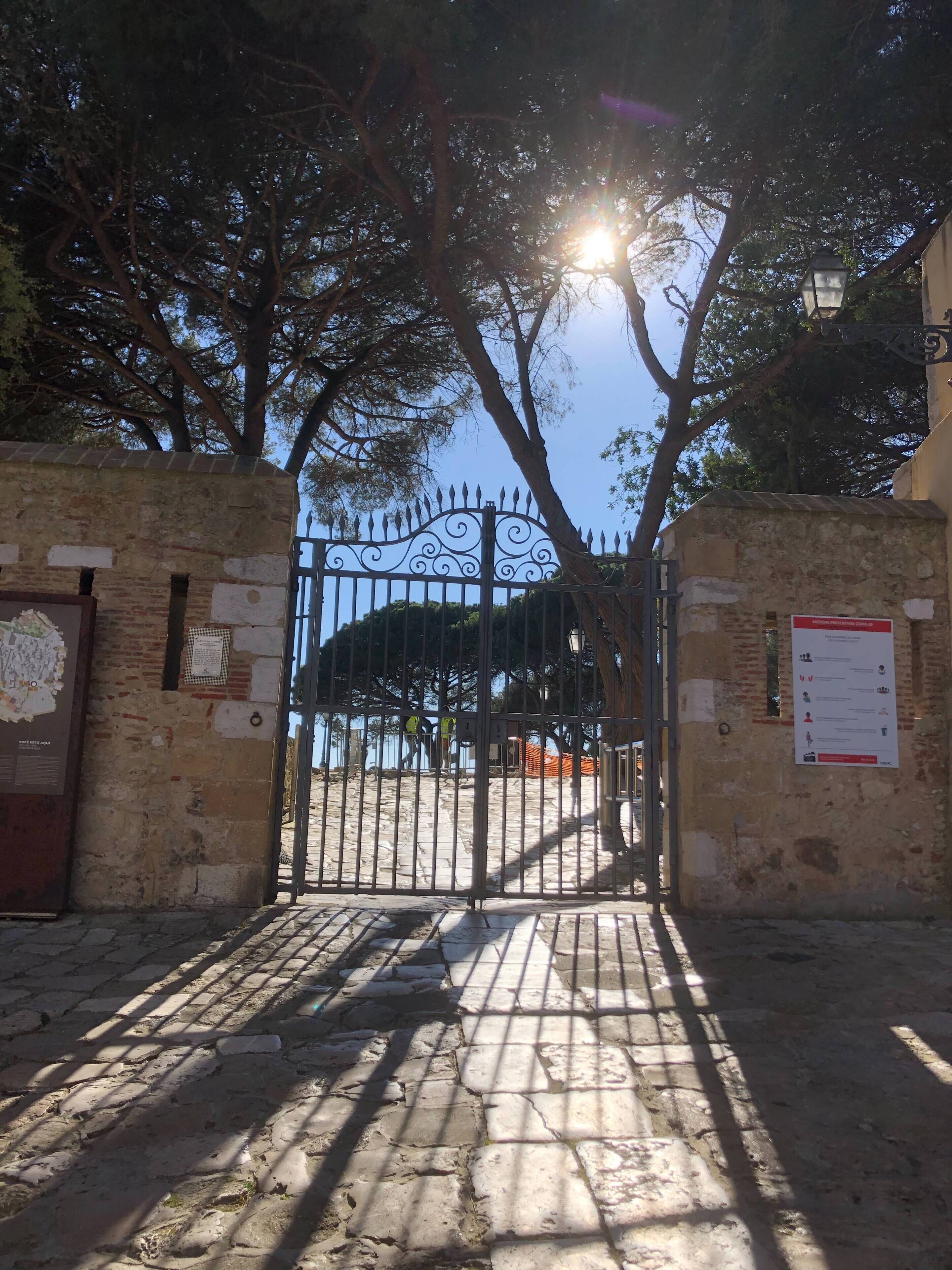 A wrought iron gate with a decorative top, leading to a paved pathway.