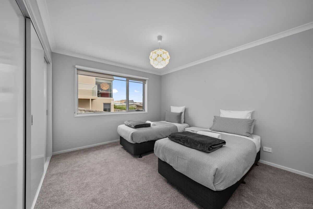 A bedroom with two beds, a window, and a ceiling light fixture.
