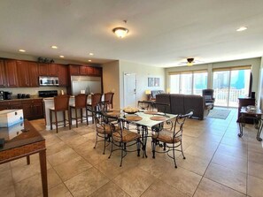A spacious kitchen with a dining area, large windows, and a balcony.
