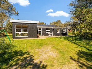 Une maison moderne à deux étages, dotée d’une grande fenêtre à l’avant, d’un patio et d’un petit garage attenant.