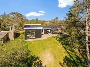 Une maison moderne à deux étages, dotée d’un grand garage, d’une terrasse et d’une pelouse bien entretenue.