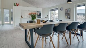 A modern kitchen with white cabinetry, a wooden dining table with six chairs, and pendant lighting. - "Helli" - 650m from the sea by Interhome (Thisted)