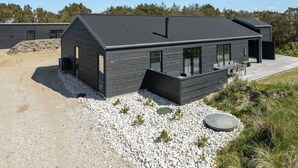 A modern house with a dark exterior, large windows, and a deck area. - "Helli" - 650m from the sea by Interhome (Thisted)