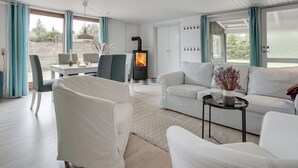 A modern living room with a fireplace, white furniture, and large windows. - "Landolf" - 250m from the sea by Interhome (Hals)