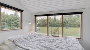 A bedroom with a bed, large windows, and a view of a forest. - "Landolf" - 250m from the sea by Interhome (Hals)